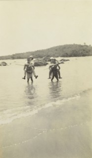 Out of water. Two European men wearing solatopi hats are carried above the water on the backs of