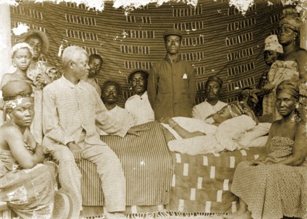 Grieving family, Western Africa. A family surround the body of a deceased female relative, lying