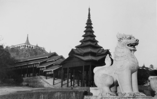 Sphinx statue at the Shwe Dagon Pagoda. A sphinx statue stands guard over a large wooden pagoda