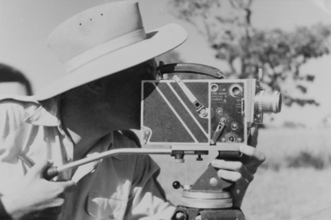 Filming for the Central African Film Unit. A European cameraman operates a movie camera on location