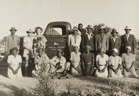 On location with the Central African Film Unit. Two European cameramen pose with the African cast