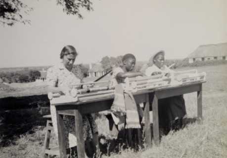Chalimbana Training College. A European and two African women weave outdoors using hand looms at