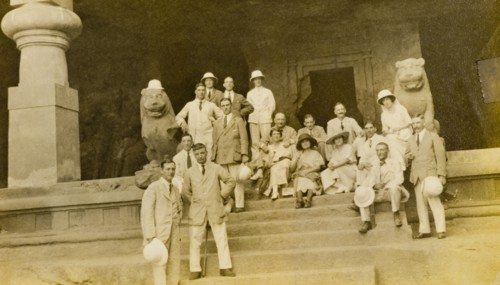 Entrance to the Elephanta Caves. A group of European visitors pose for the camera on steps outside