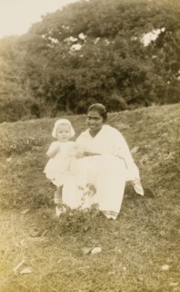 Ayah with toddler. Outdoors portrait of a young British toddler, posing for the camera with her