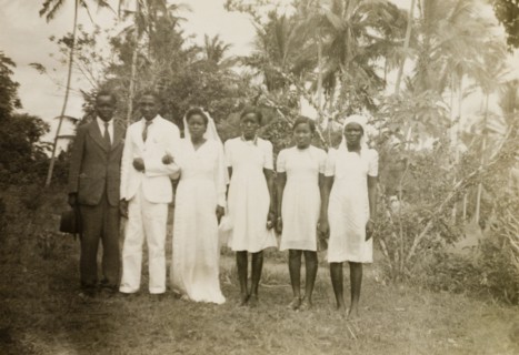 A European-style African wedding. A newlywed African couple pose outdoors with their best man and