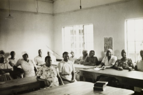 The wives of trainee priests attend college. The wives of trainee priests sit at their desks in a
