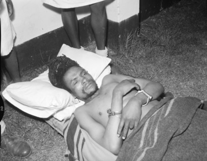 Portrait of Dedan Kimathi. Dedan Kimathi lies handcuffed on the ground shortly before his execution