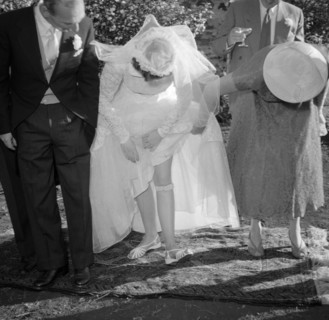 A bride reveals her garter. The bride at the Carey-Courtney wedding lifts up her wedding dress to