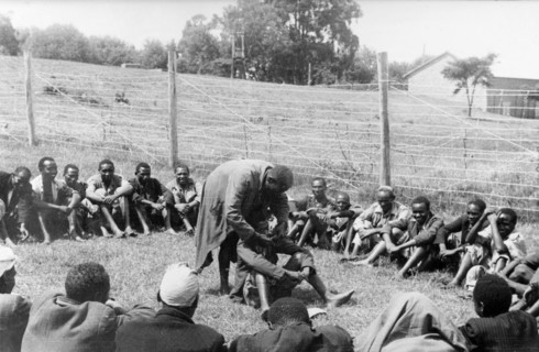 Government de-oathing ceremony. A Mau Mau detainee sitting in the centre of a circle of men in a