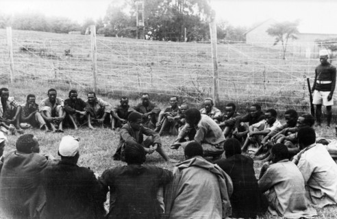 Government de-oathing ceremony. A Mau Mau detainee sitting in the centre of a circle of men in a
