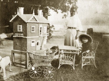 Marjory Wood's dollhouse. A young girl identified as 'Marjory Wood' sits at a miniature table