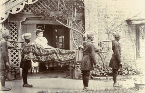 Mem Sahib Blount goes visiting. Mem Sahib Blount reclines in an open sedan chair as she is carried