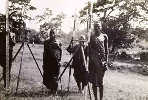 Maasai men help a surveying team. Four Maasai men in traditional dress help a surveying team by