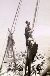 A 'gully gully' man. An Egyptian 'gully gully man' (travelling magician), perches high on the mast