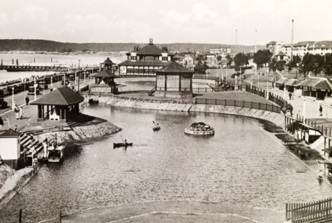 Children's outdoor pool, Durban. Two children paddle canoes on an outdoor boating pool near the