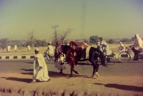 Hurrying to a celebration. Pedestrians and cyclists hurry along a road to a celebration marking the