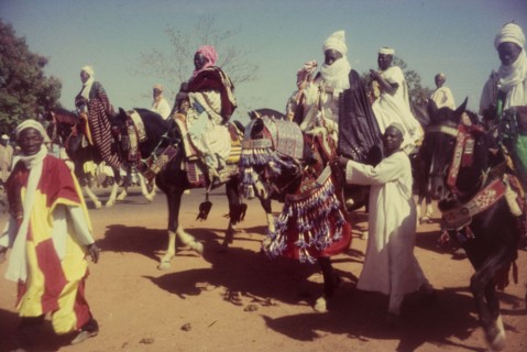 Decorated horses, Nigeria. Men dressed in ceremonial attire ride horses decorated with tassles and