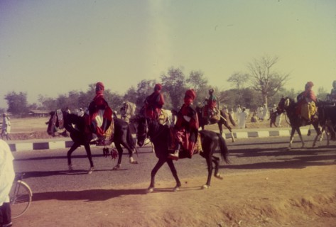 Procession for Ramadan. A group of Nigerian men dressed in ceremonial attire ride horseback in a