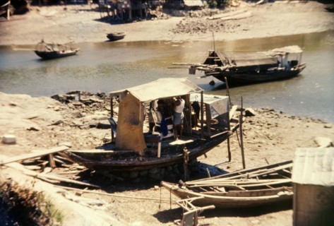 Barber's shop on a Chinese sampan. A small sampan grounded on the shore, serves as an unusual
