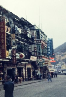 Street scene in Kowloon. Shopfronts on a busy city street are littered with signs written in