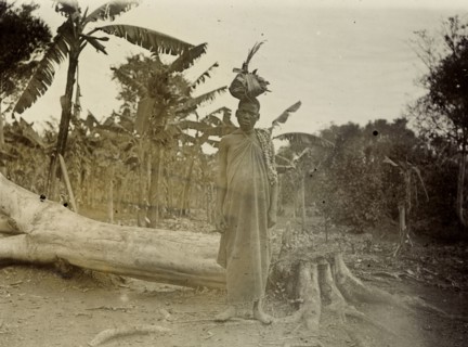 Collecting peanuts, Uganda. A Ugandan woman gazes seriously into the camera. She stands beside a