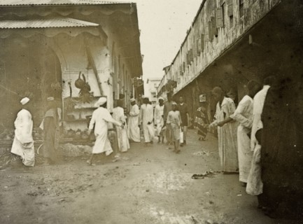 Zanzibar 'business quarter'. Men in long robes walk purposefully along a busy, narrow road in the