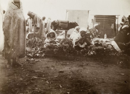 Market scene, Casablanca. Street traders crouch on the ground, trying to sell fruit and vegetables