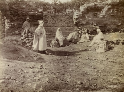 Morrocan men at a ruin. A group of Moroccan men dressed in white robes gather beside a ruin in the