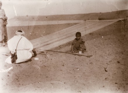 Rope making, Morocco. A Moroccan man works in the desert, stretching fibres onto a frame before