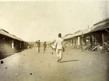 Indian bazaar, Nairobi. A man walks down a wide street lined with low shops, the main Indian bazaar