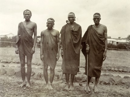 Four Kikuyu men. Group portrait of four Kikuyu men wearing traditional dress and jewellery. British