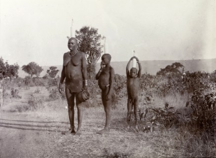 Luo woman and children carrying milk. A Luo women and her two children balance tall bottles of milk