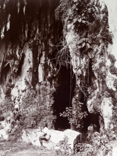 Entrance to the Batu Caves. Two Tamil men sit outside the entrance to the Batu caves in the jungle.
