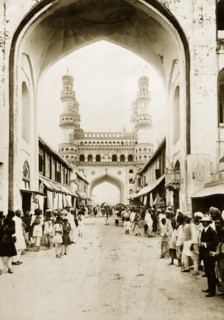The Char Minar in Hyderabad. Pedestrians line a street running towards the Char Minar. Hyderabad,