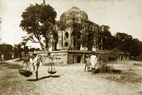Ruined mosque, Serampore. A man carries baskets on a pole over his shoulder at the site of a ruined