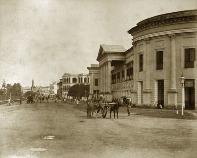 Strand Road in Rangoon. Pedestrians and cattle-drawn carts meander along Strand Road. Rangoon