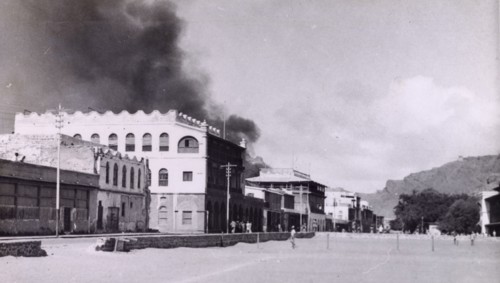 Riot damage in Aden, 1947. A plume of black smoke rises from a building in the Jewish quarter of