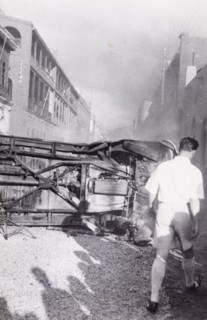 Aftermath of Arab riots in Aden, 1947. A European man walks around an upturned truck lying in the