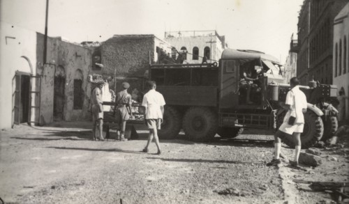 Clearing up after Arab riots in Aden, 1947. Soldiers maneuver a utility truck through a street in