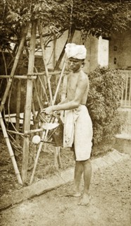 Watering the garden, India. A turbaned Indian man sprinkles water onto a dusty garden from a