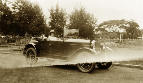 Driving in the grounds. A European woman poses for the camera from an open-topped car in the