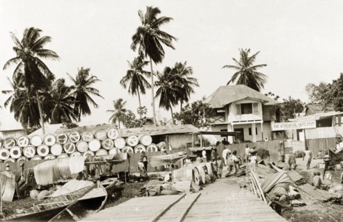 Palm oil storage yard. Barrels of palm oil wait to be collected by boat at a riverside storage yard