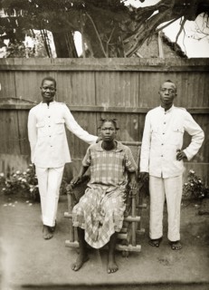 Portrait of domestic servants. Portrait of two male domestic servants and a woman in a garden.