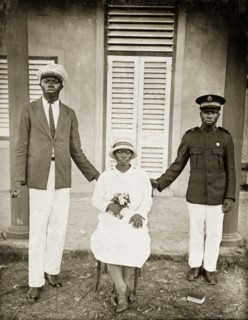 Portrait of Salvation Army workers. Two African men in Western dress stand on either side of a