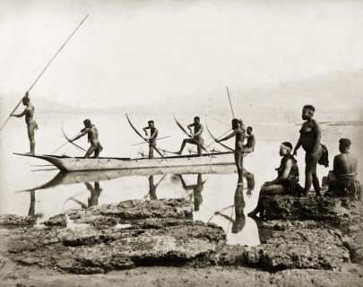 Andaman Islanders fishing. Six nearly naked men stand in a canoe, or in shallow water beside it,