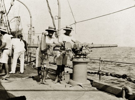 A gun on RIMS 'Minto'. British naval officers pose, leaning on a three pound gun on the deck of