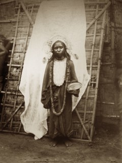 Young mendicant girl. A young female mendicant stands, bowl in hand, dressed in a headdress, a