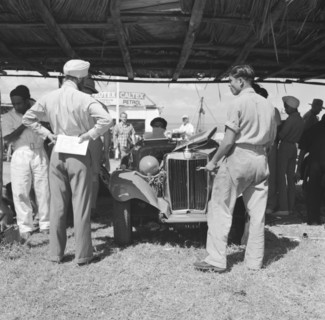MG at the Langa Langa Races. An Asian man ponders the open engine of an MG car in the paddock at