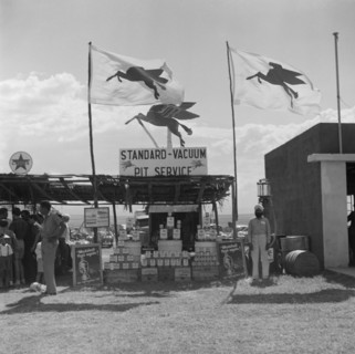 Standard-Vacuum Pit Service'. A turbaned Indian man stands beside a stall selling Mobil oil at the