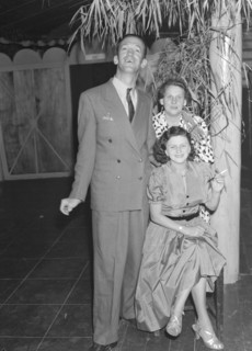 Guests at a Christmas party. Mr and Mrs Morris pose for the camera with Mrs Holmes at a Christmas